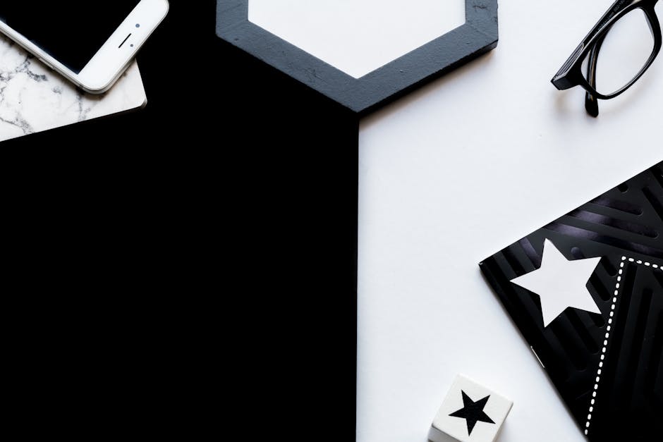 Stylish flat lay composition featuring a smartphone, glasses, and star-themed decorations on a black and white background.